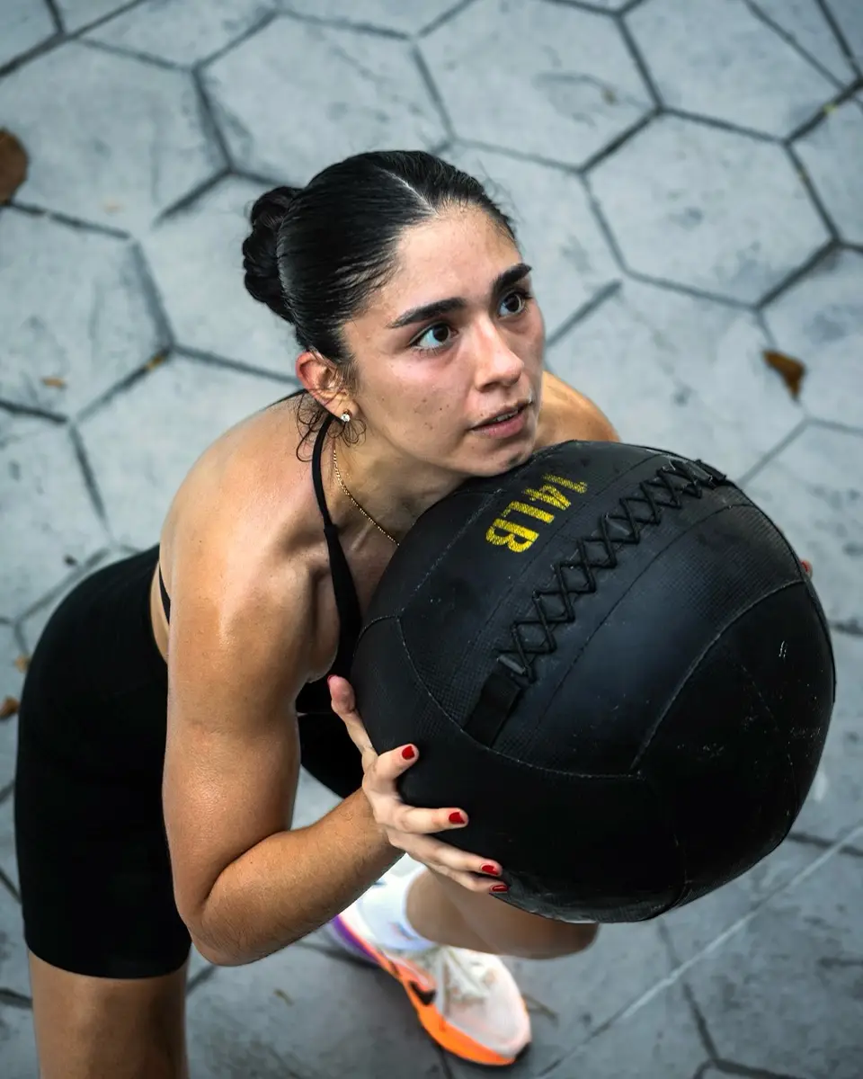 Una corredora sostiene un balón medicinal con las dos manos, lista para el siguiente ejercicio del circuito.
