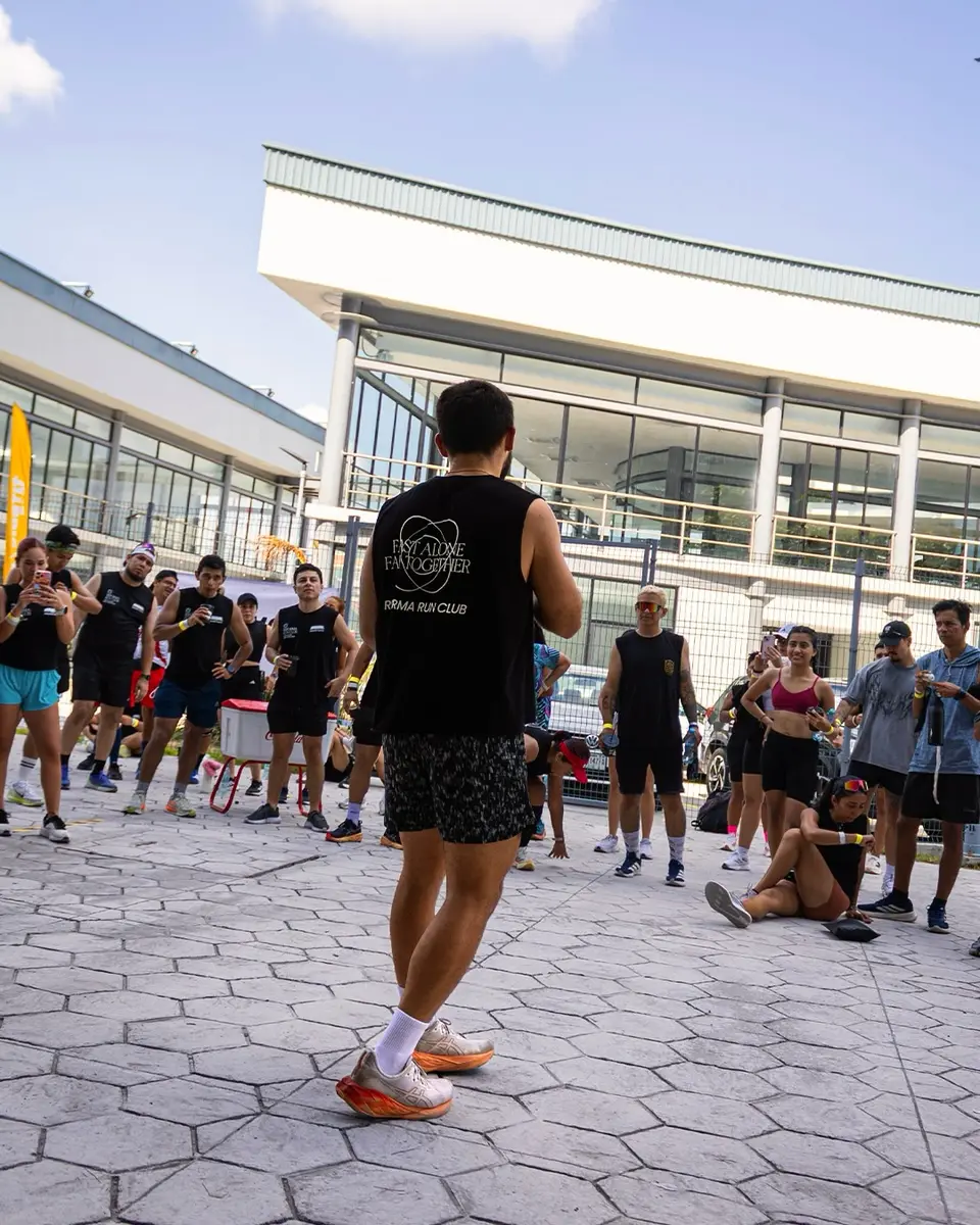 Un corredor camina de regreso hacia el grupo, que descansa sentado en la explanada después de la corrida.